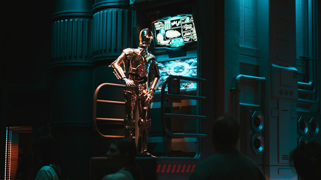 Camera operator filming inside a television studio with lighting rigs overhead